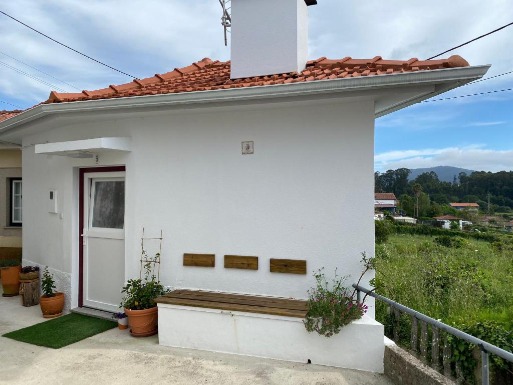 een wit huis met een bankje ervoor bij Casa do Montinho in Caminha