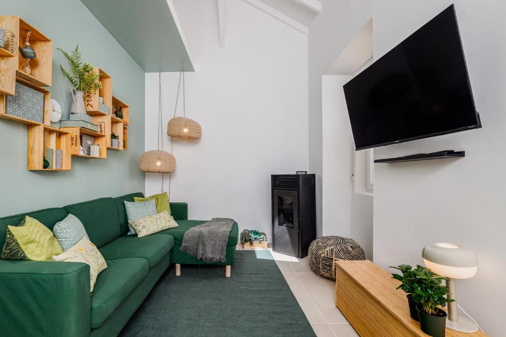 a living room with a green couch and a flat screen tv at Avenca da Praia - Tiny House 4 Beach & Surf Lisbon Getaway in Parede