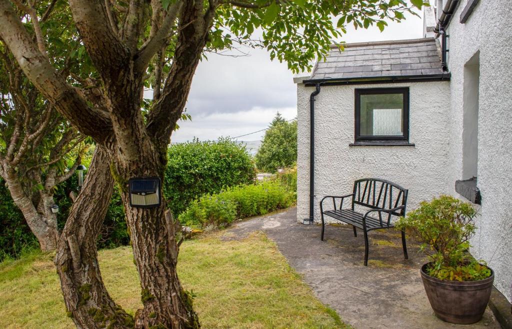 a bench sitting next to a house next to a tree at 5 Galtrigill in Dunvegan