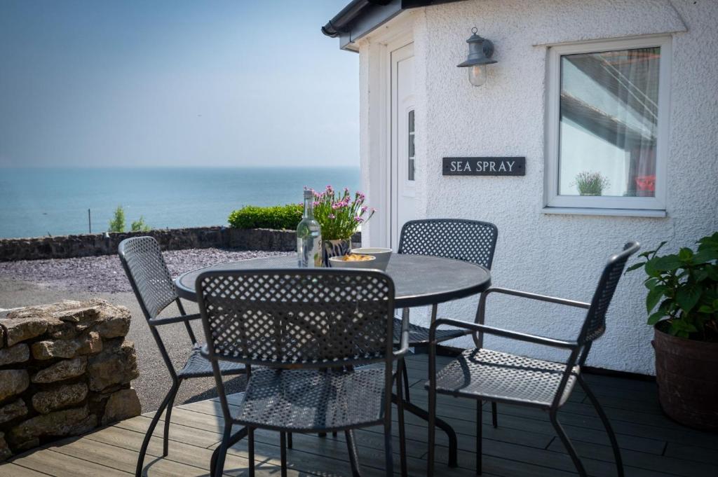 a table and chairs on a patio with the ocean at Sea Spray in Moelfre
