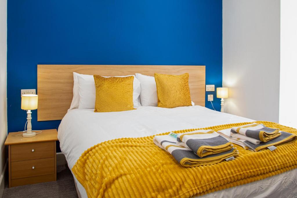 a bed with a yellow blanket and a blue wall at The Highlands, Bispham in Blackpool