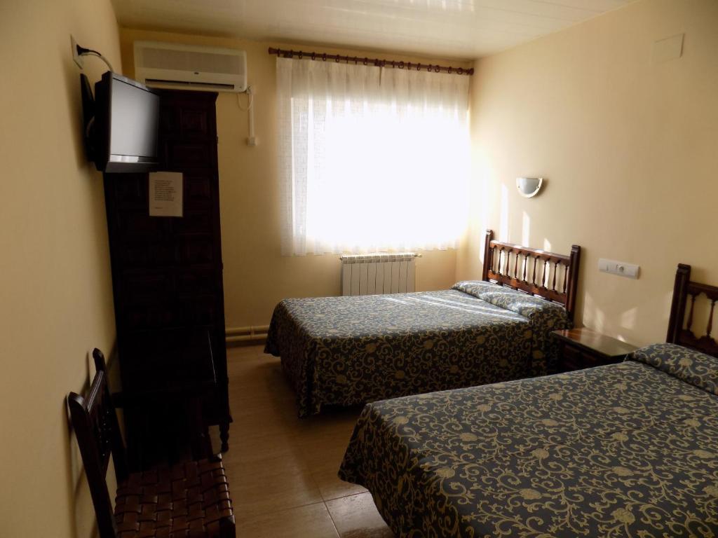a hotel room with two beds and a window at Hostal Amigo in Ocaña