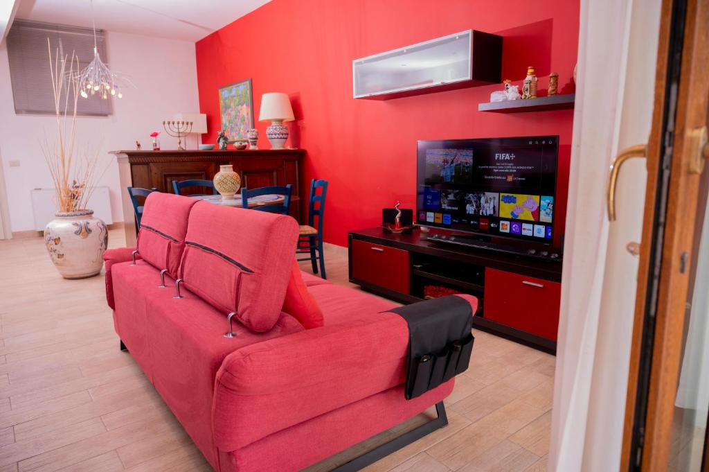 salon z czerwoną kanapą i telewizorem w obiekcie Dimora Belvedere w Alberobello