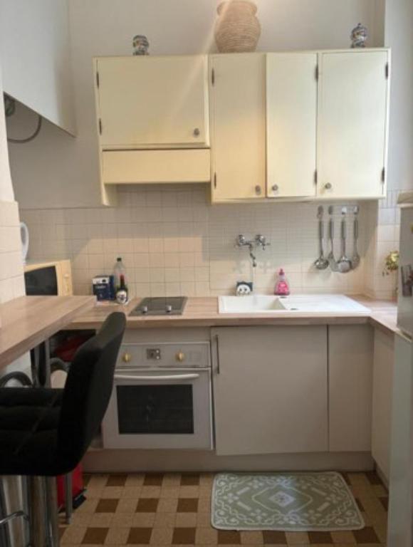 une cuisine avec des armoires blanches, un évier et une cuisinière dans l'établissement Little garden, à Nice