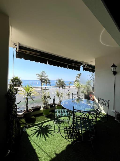 Cette chambre dispose d'une table et offre une vue sur la plage. dans l'établissement Appartement Promenade, à Nice