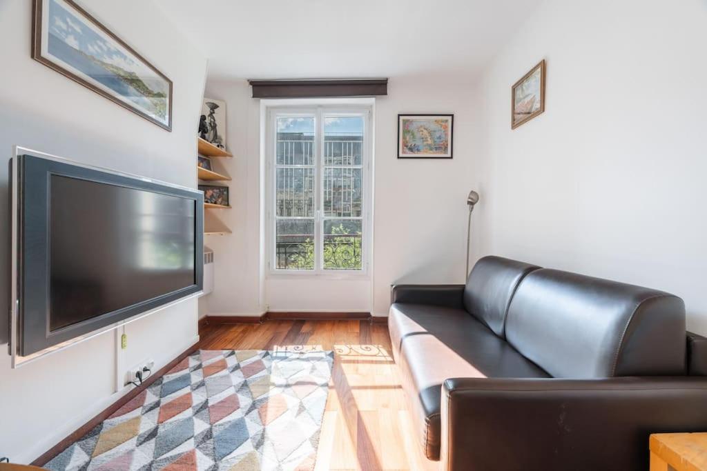 - un salon avec un canapé en cuir noir et une télévision à écran plat dans l'établissement A cosy 1-BDR in Montparnasse, à Paris
