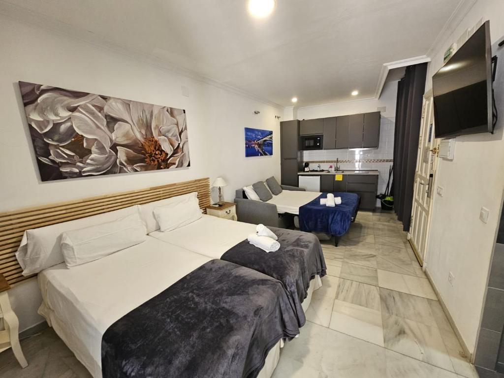 een hotelkamer met twee bedden en een woonkamer bij Apartamentos Los Angeles in Sevilla