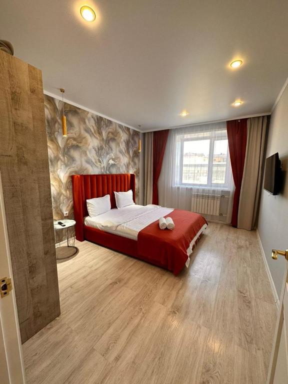 a bedroom with a large bed with a red blanket at Квартира в новом ЖК Абай in Kokshetau