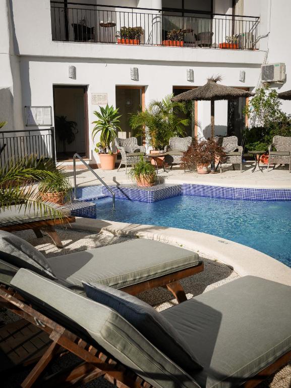 a swimming pool with lounge chairs next to a building at Las Palmeras del Califa in Vejer de la Frontera