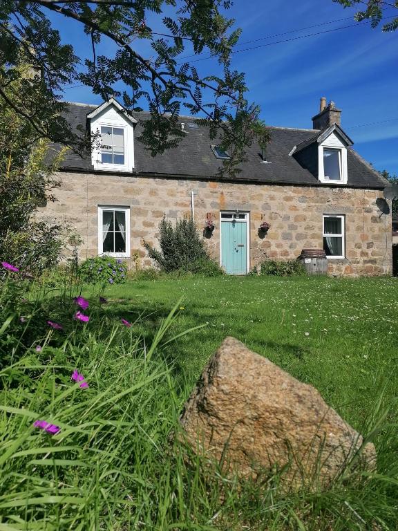 a stone house with a blue door in a yard at Aberlour Cottages - Bolthole & Retreat in Aberlour