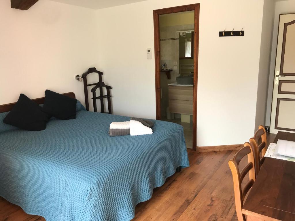 a bedroom with a blue bed and a bathroom at La maison de Laujol in Moissac