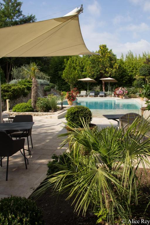 - une piscine avec un parasol, des tables et des chaises dans l'établissement Domaine de Mejeans - Teritoria, à Alleins