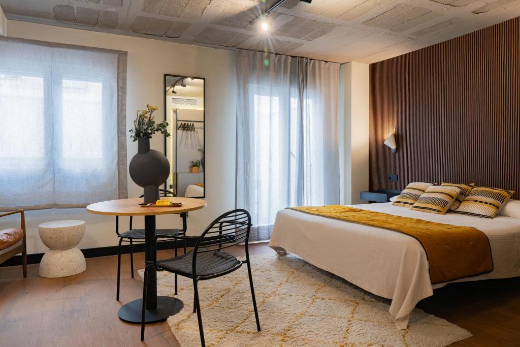 a bedroom with a large bed and a table and chair at BUBU Apartments By Charming Stay in Málaga