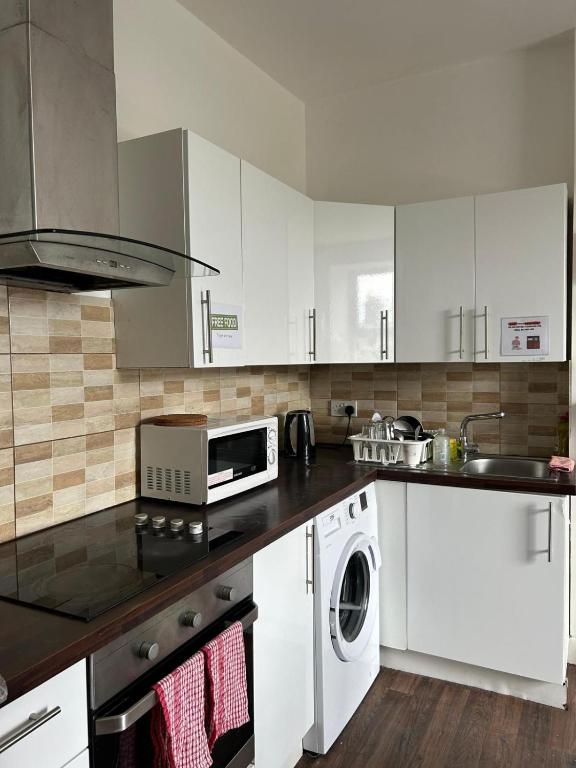 a kitchen with white cabinets and a washer and dryer at Sarsfields Communities in Dolphinʼs Barn