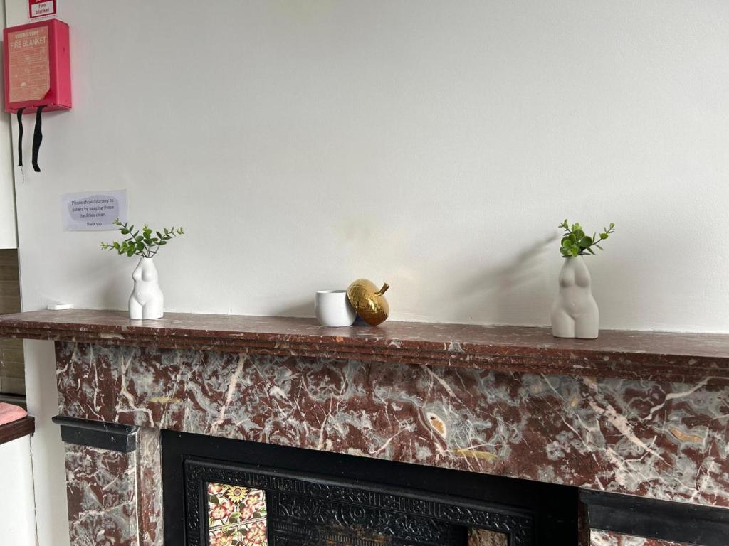 a fireplace with three vases on top of it at Sarsfields Communities in Dolphinʼs Barn