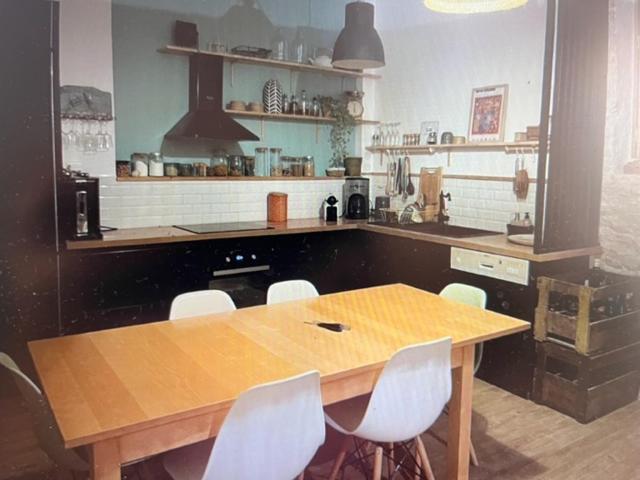 - une cuisine avec une table en bois et des chaises blanches dans l'établissement Charmante maison de vacances, à Saint-Michel-Chef-Chef