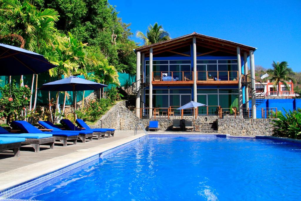 a resort with a swimming pool with chairs and umbrellas at Kayu Hotel in El Sunzal