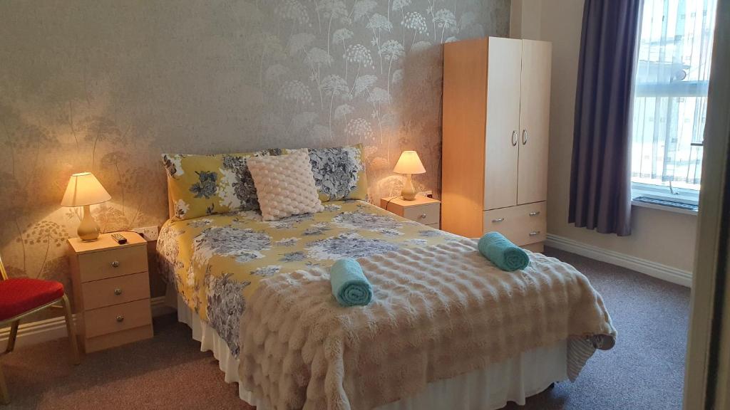 a bedroom with a bed with two blue towels on it at The Tudor in Blackpool