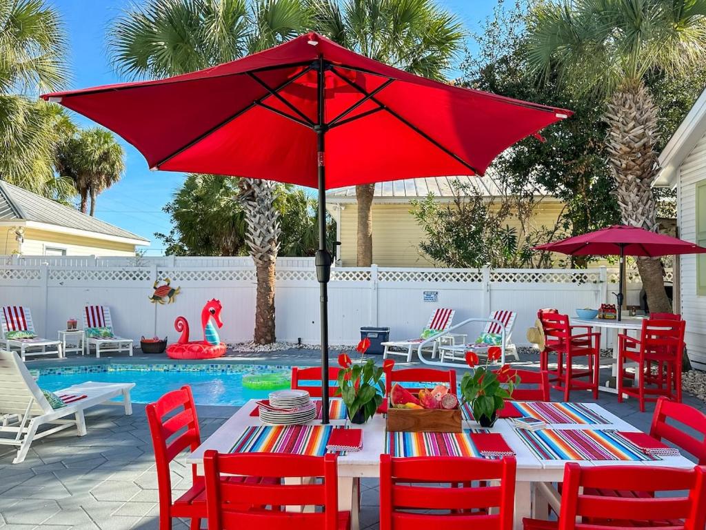 ein roter Sonnenschirm auf einem Tisch mit Stühlen und einem Pool in der Unterkunft SolMate Free Golf Cart & Pool Heat Deals in Destin