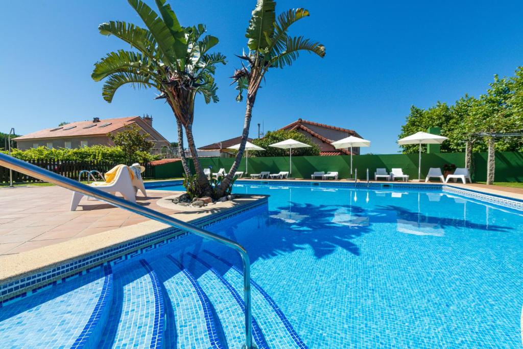 a swimming pool with palm trees and umbrellas at Hotel Gaivota in Montalvo