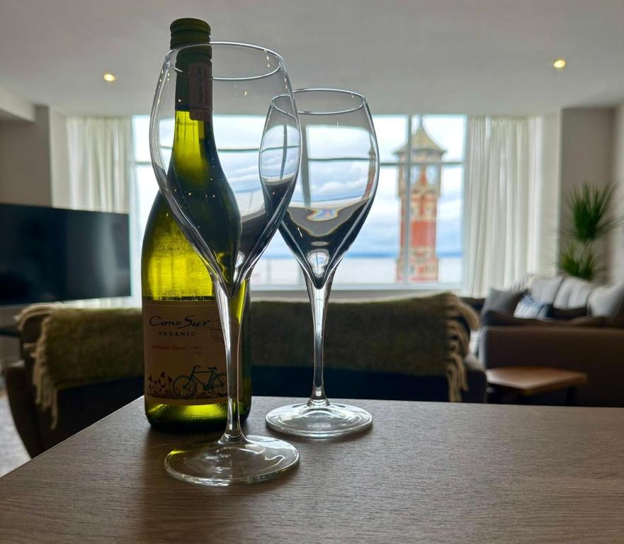 a bottle of wine and two glasses on a table at Clock Tower Apartments 1 in Morecambe
