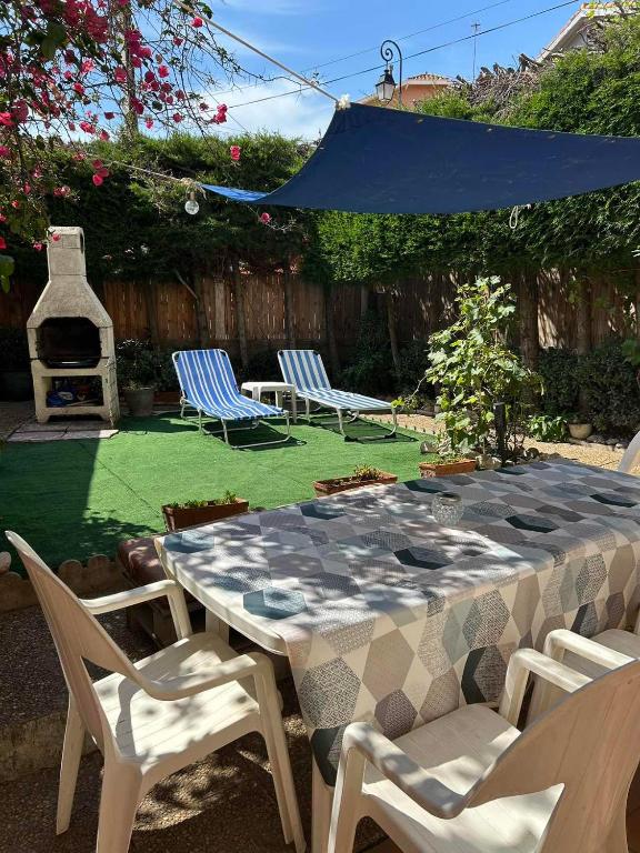 une table et des chaises dans une arrière-cour avec un grill dans l'établissement Maison de village Canet en Roussillon proche mer, à Canet