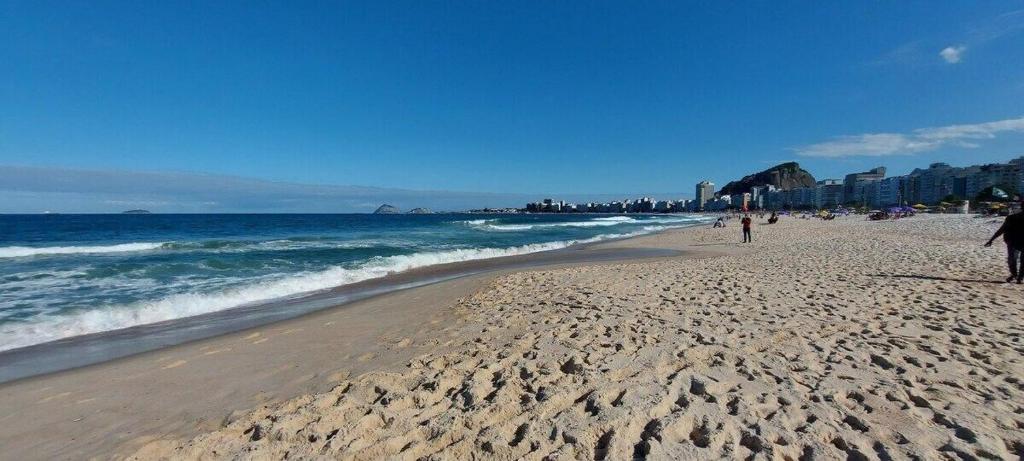 a beach with people walking on the sand and the ocean at SUH Copacabana 01 Nice Balcony Close To Beach in Rio de Janeiro