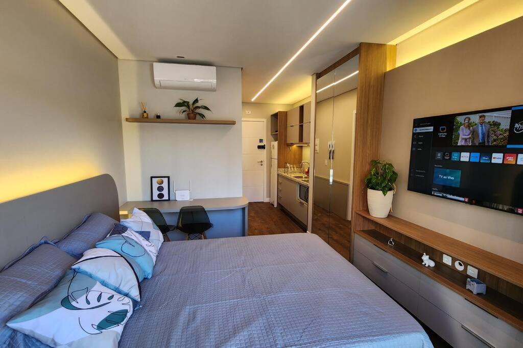 a bedroom with a bed with a flat screen tv at Studio Novo Alto Padrão - Centro in Curitiba