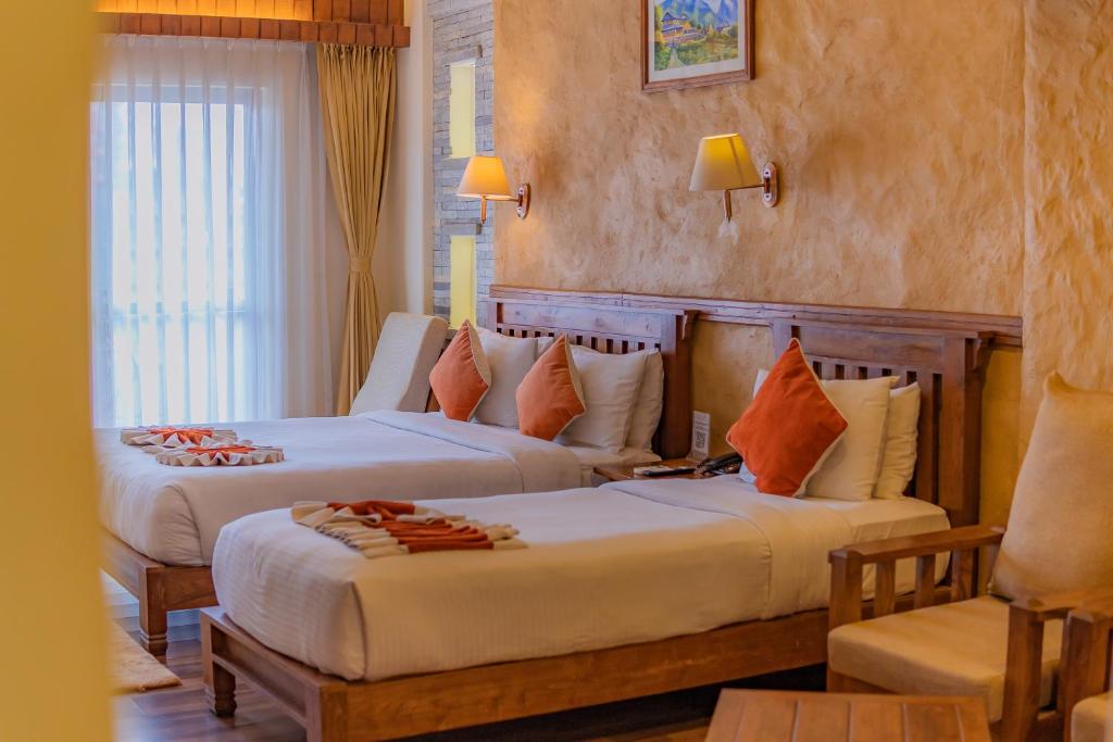 a bedroom with two beds and a chair in it at Pokhara Batika in Pokhara