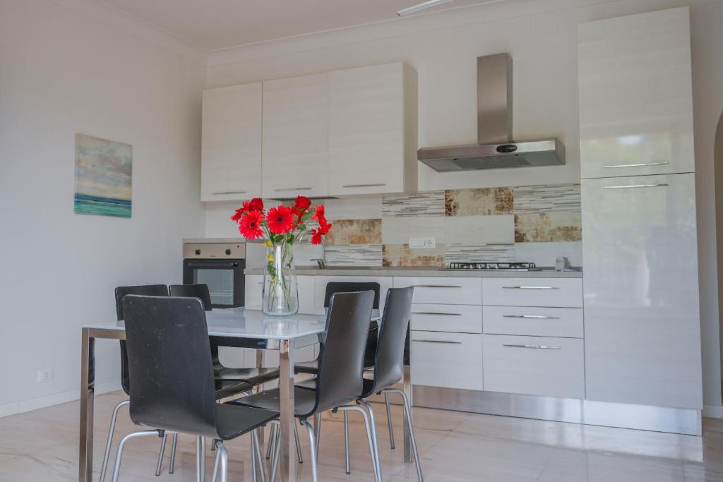 a kitchen with a table with chairs and a vase with red flowers at Halanus Agriexperience in Alanno