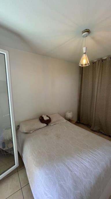 une chambre avec un lit blanc et un miroir dans l'établissement T2 parking avec balcon, à Nîmes