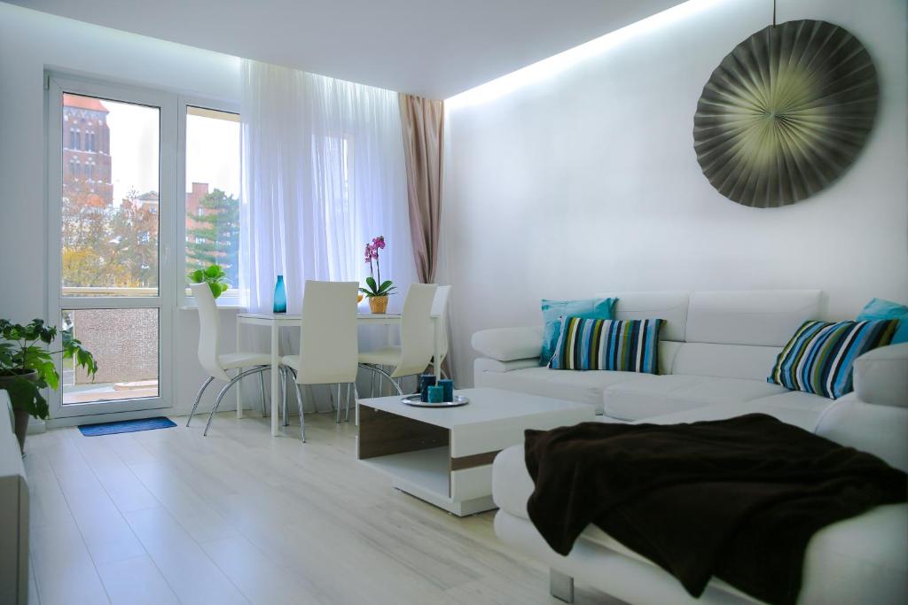 Apartament Świętojańska في غدانسك: غرفة معيشة بيضاء مع أريكة بيضاء وطاولة