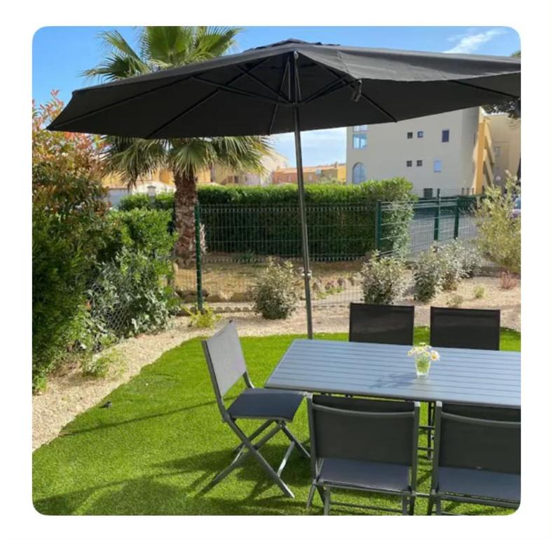 - une table et des chaises avec un parasol dans la cour dans l'établissement Appartement 6 couchages rez-de-jardin à 5 mn de la plage, au Cap d'Agde