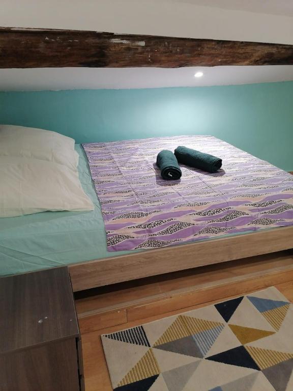 un lit avec une couette violette et deux bouteilles dessus dans l'établissement Chez Gabin & Elsie, à Pertuis