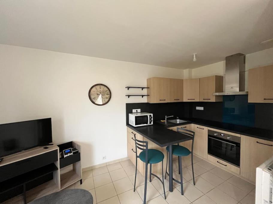 une cuisine avec une table et une horloge au mur dans l'établissement Les Tilleuls, à Saint-Planchers