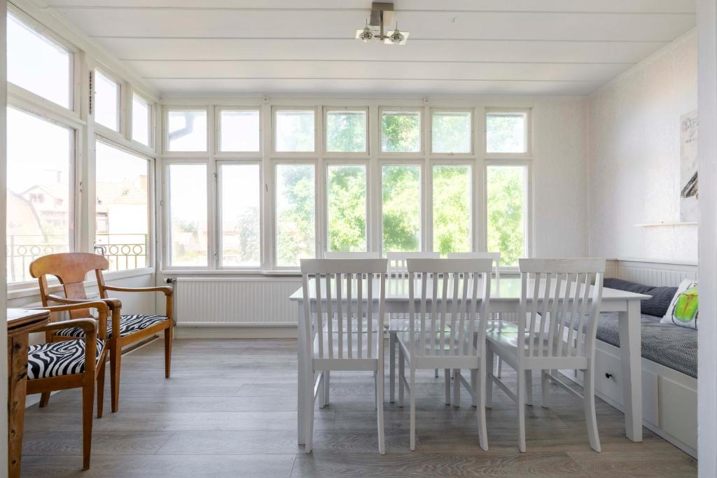 une salle à manger avec une table, des chaises et des fenêtres dans l'établissement Beautiful 3 bedroom apartment in heart of Visby, à Visby