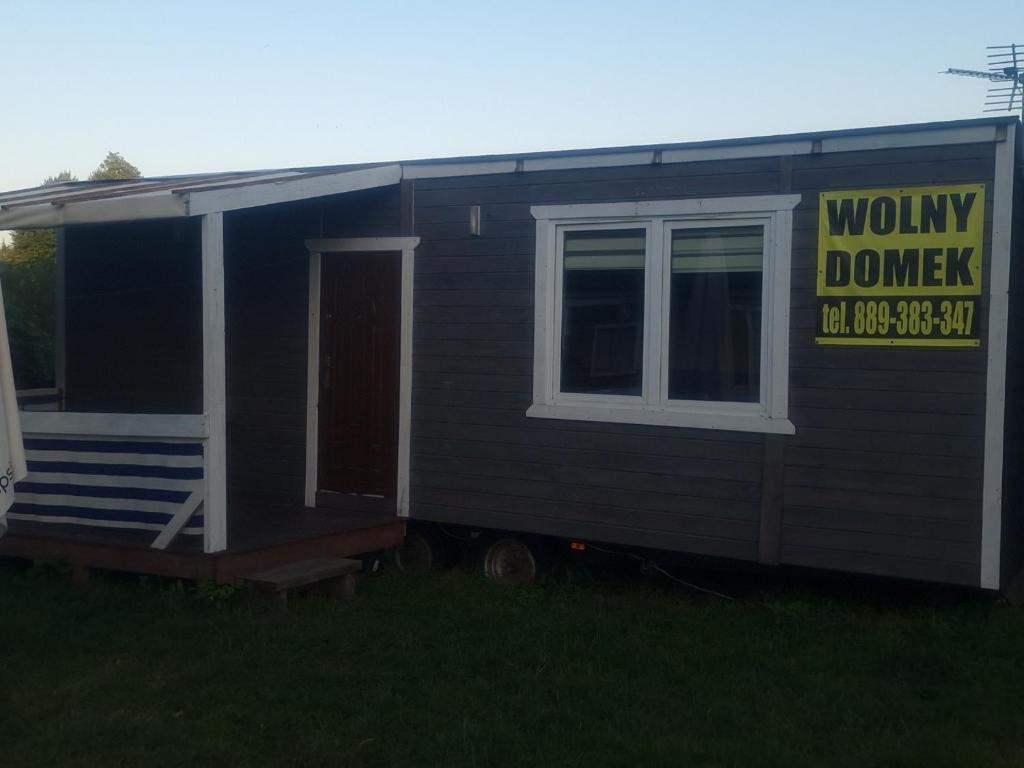 a tiny house with a sign on the side of it at Apartament HOLENDER na Polu namiotowym RADOŚĆ in Okuninka