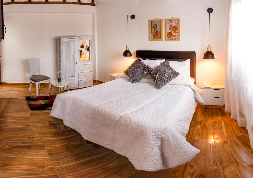 a bedroom with a white bed and a wooden floor at Hotel Olivar de La Villa in Villa de Leyva