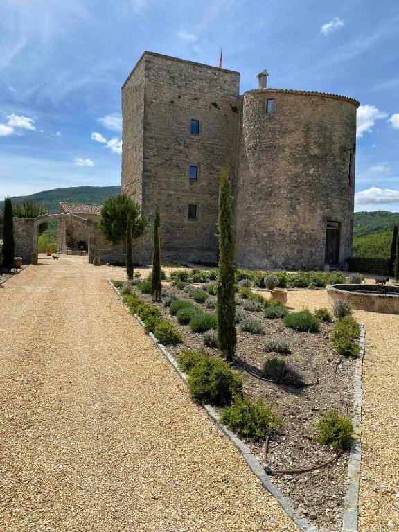 un grand bâtiment en briques avec des arbres devant lui dans l'établissement Chateau de Sainte Jalle, à Sainte-Jalle