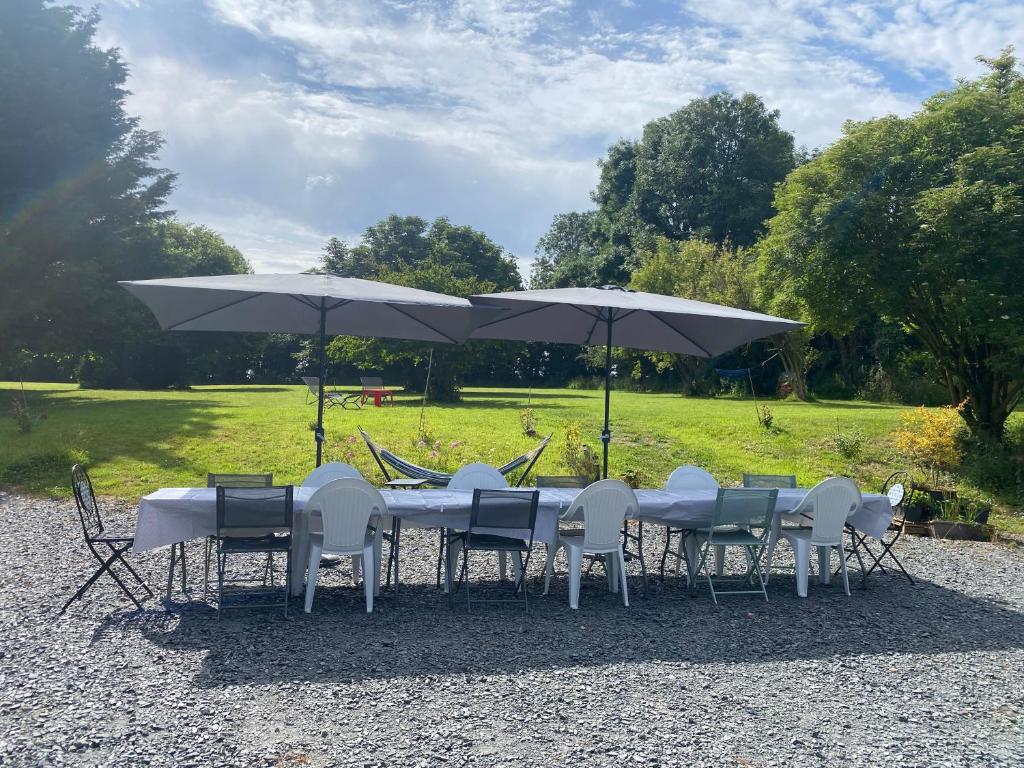 a table and chairs with umbrellas in a park at Le Domaine Des Roses Normandie Foulognes in Foulognes