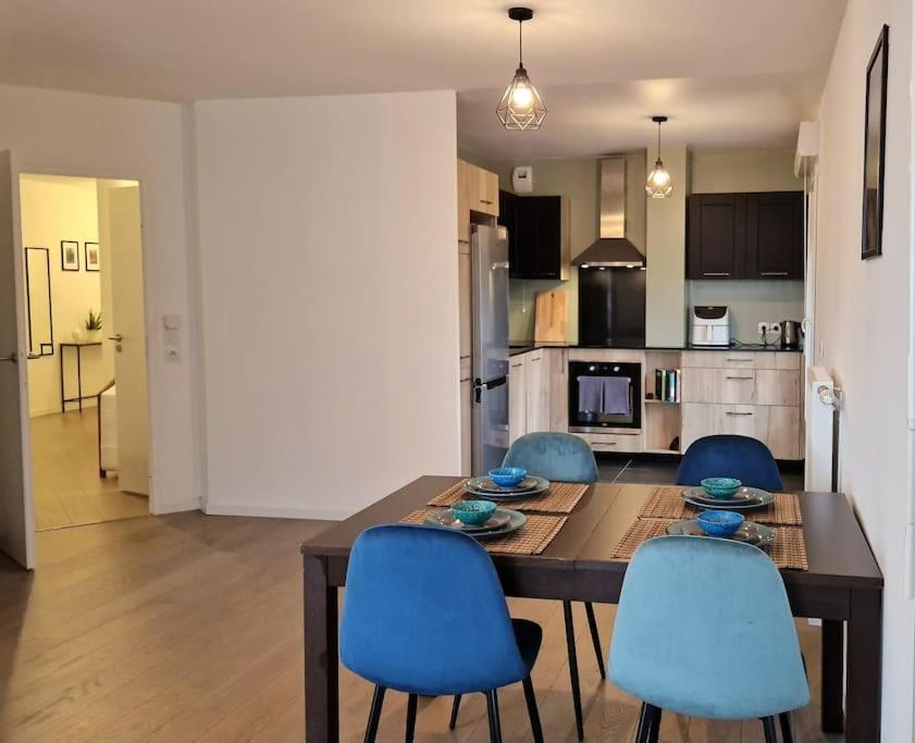 une cuisine avec une table en bois et des chaises bleues dans l'établissement Appartement Chic près de Paris - Parking & Terrasse, à Gennevilliers