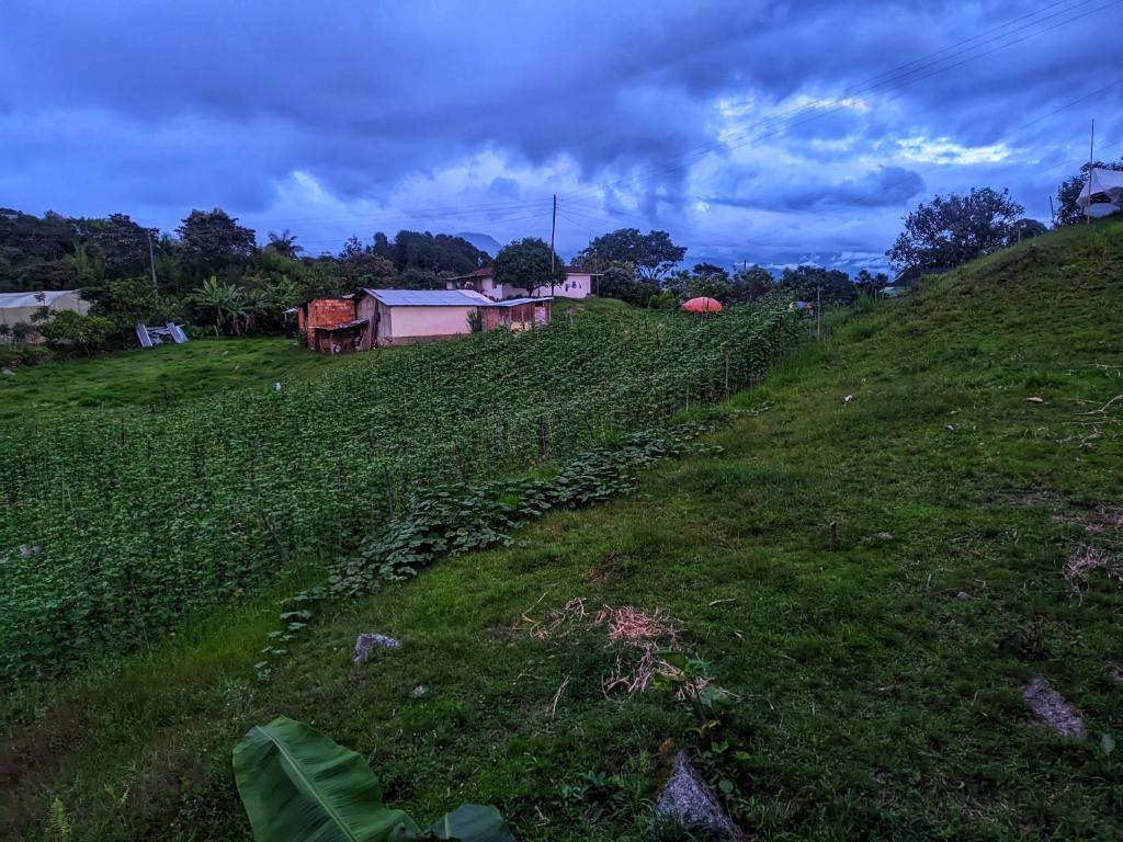 a grassy hill with a house and a field at El Monolito Camping in Ubaque