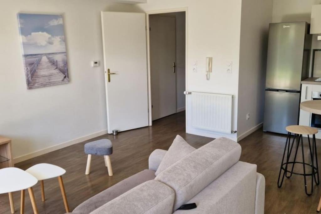 Il comprend un salon avec un canapé et des tables ainsi qu'une cuisine. dans l'établissement Appartement ensoleillé, à Les Sables-dʼOlonne