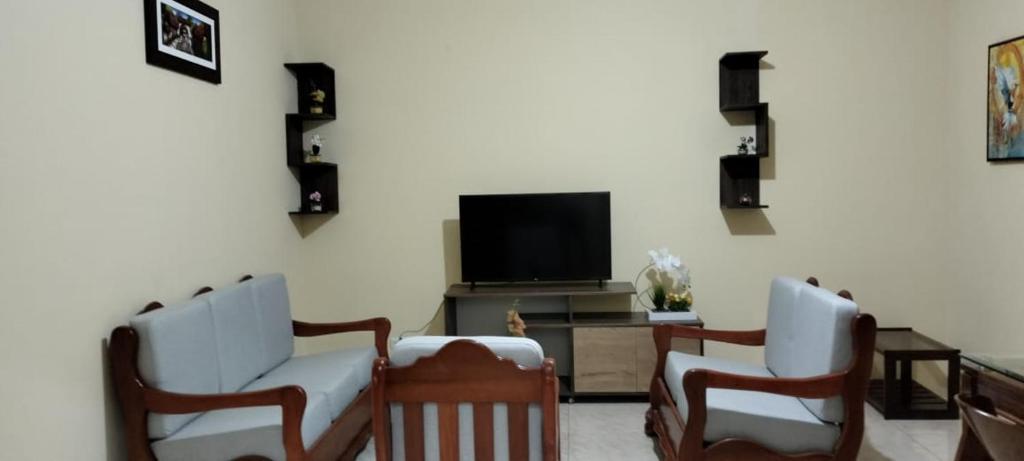 a living room with two chairs and a flat screen tv at Departamentos las Palmeras in Tarapoto