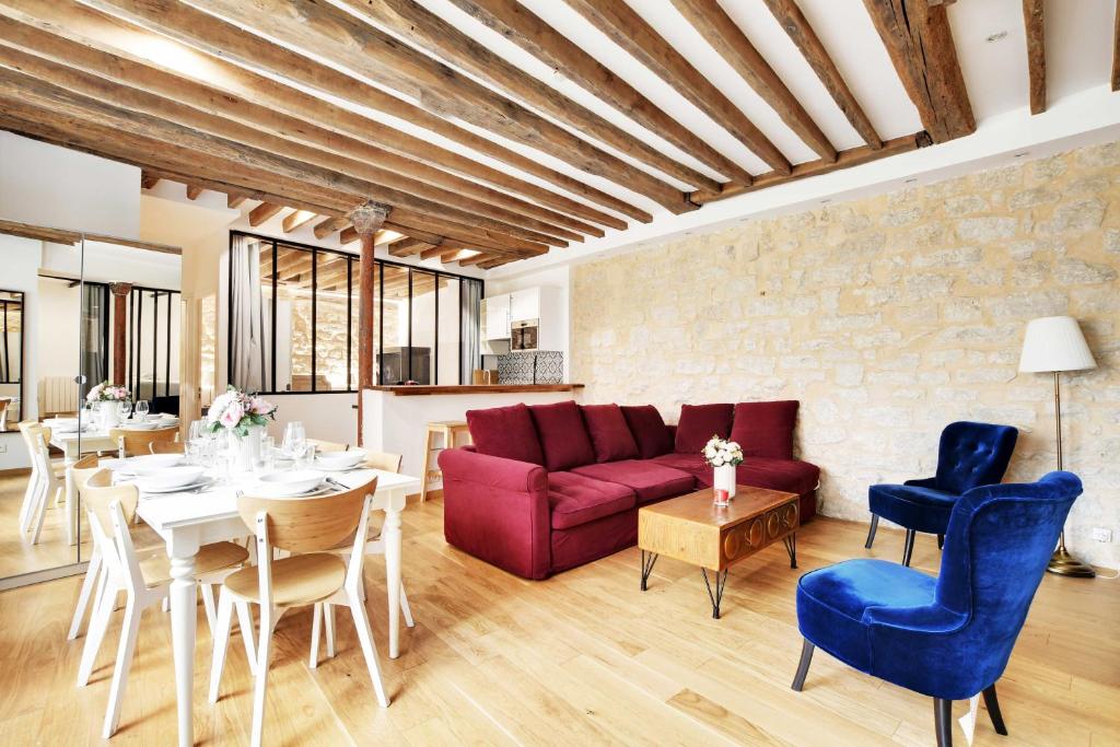 - un salon avec un canapé rouge, des tables et des chaises dans l'établissement Appartement Chic au Cœur du 9ème 2 chambres 6P, à Paris