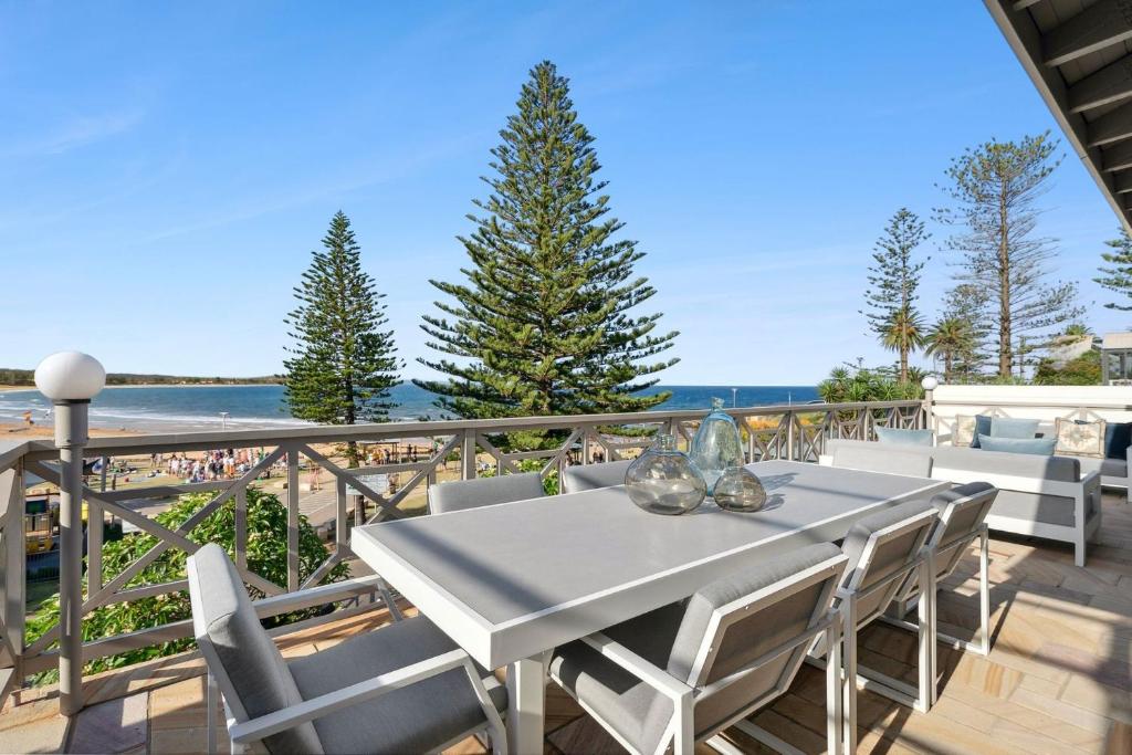 a table and chairs on a balcony with the beach at Kaya in Collaroy