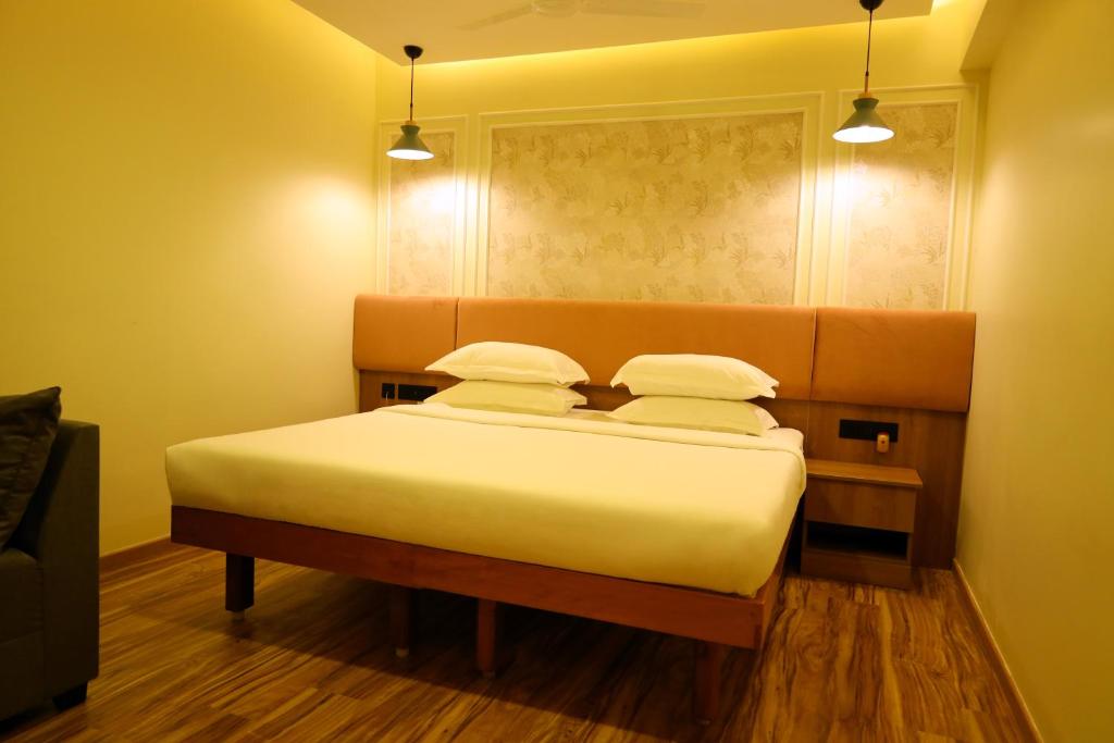 a bedroom with a large bed with two pillows at Hotel Surguru in Puducherry