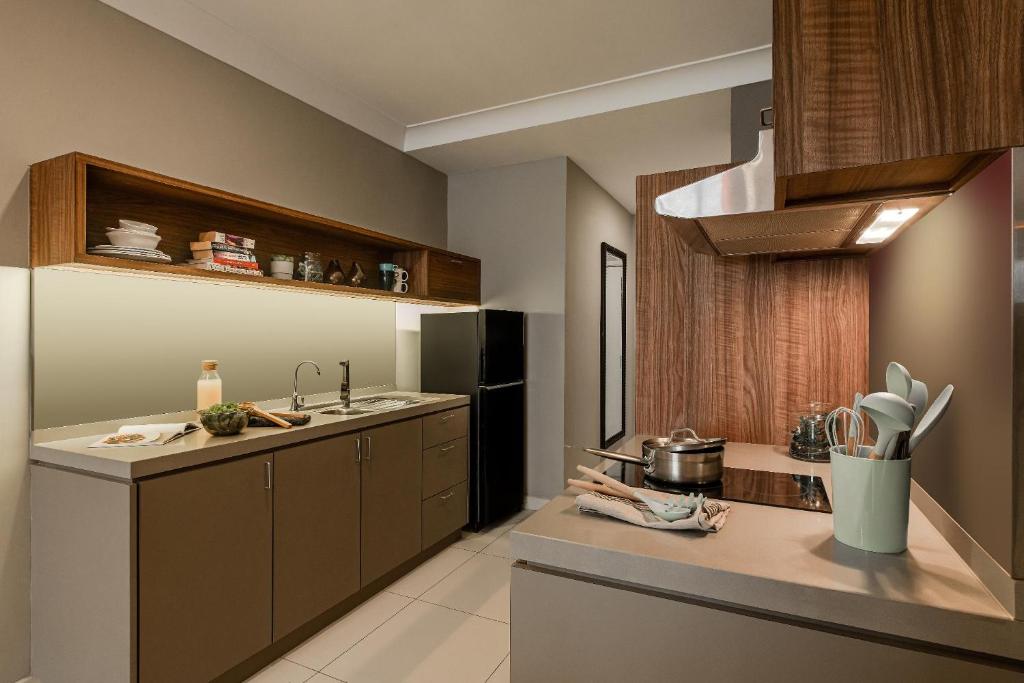 A compact fitted kitchen provides a sink, refrigerator, cooktop and overhead extraction.