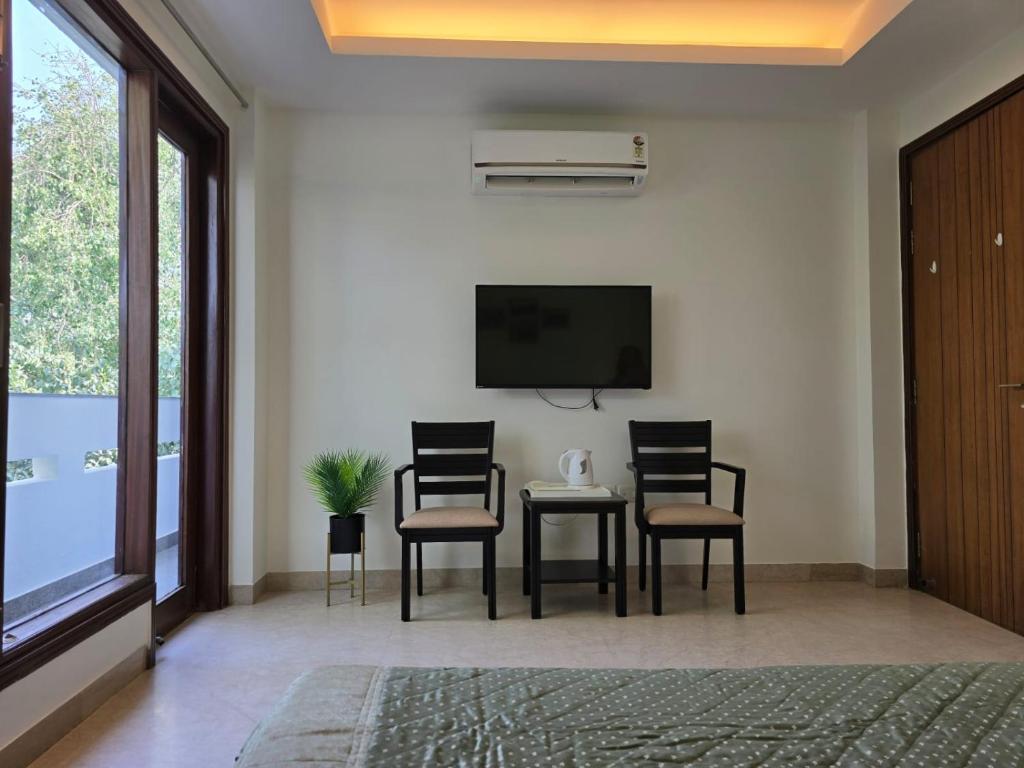 a living room with two chairs and a table and a tv at Two Green Park in New Delhi