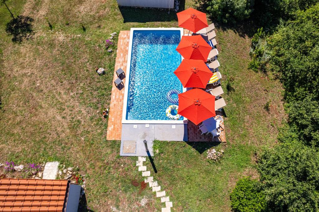 einen Blick über einen Pool mit roten Sonnenschirmen in der Unterkunft Villa Mina - Orihi in Orihi